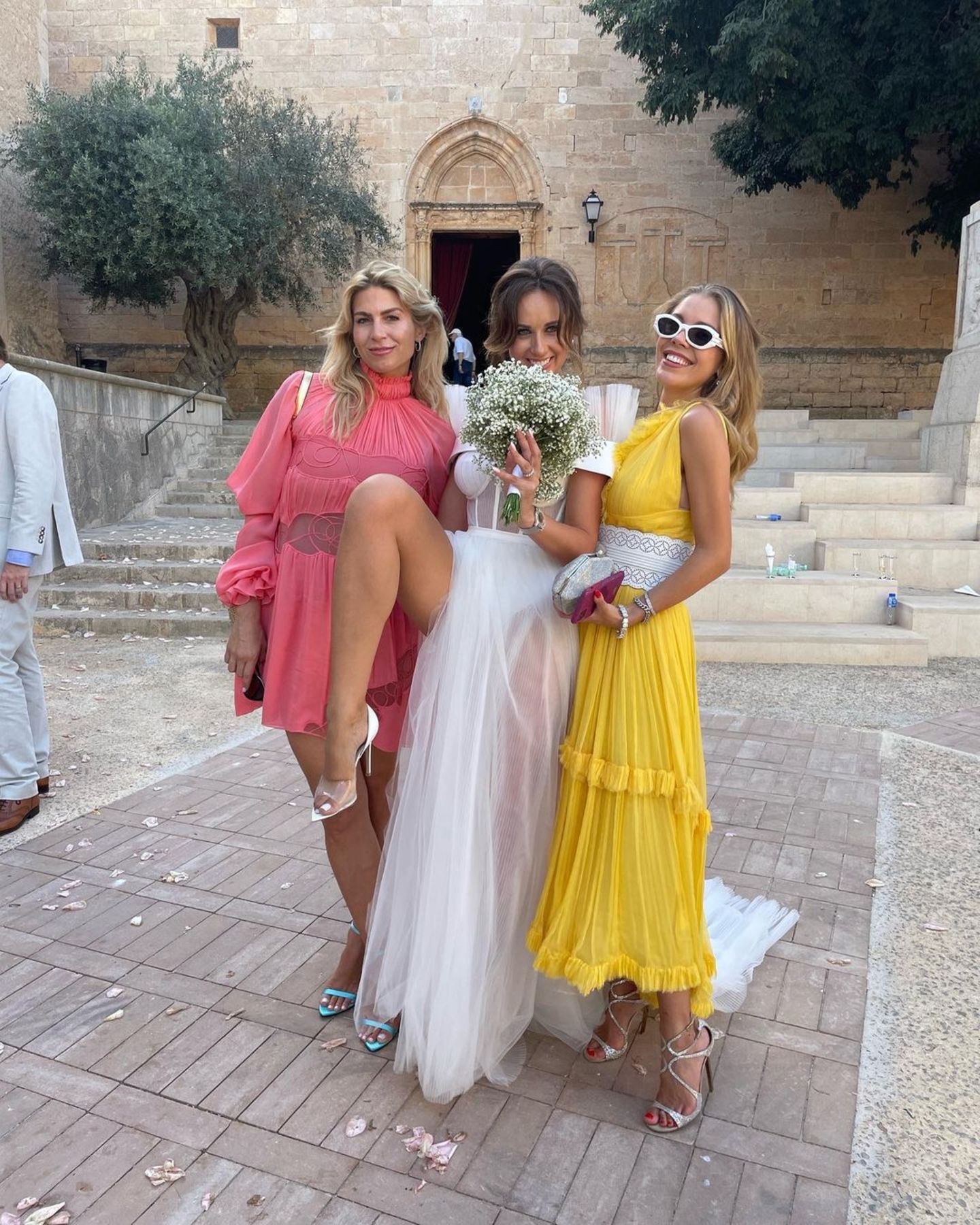 Bei der Hochzeit einer Freundin ist Victoria Swarovski wieder einmal ein absoluter Hingucker. Sie trägt ein strahlend gelbes, fließendes Kleid mit einem auffälligen weißen Taillengürtel. Glitzernde Strap-Heels, die passende Clutch und eine große Sonnenbrille sind die perfekten Begleiter für ihren Look.