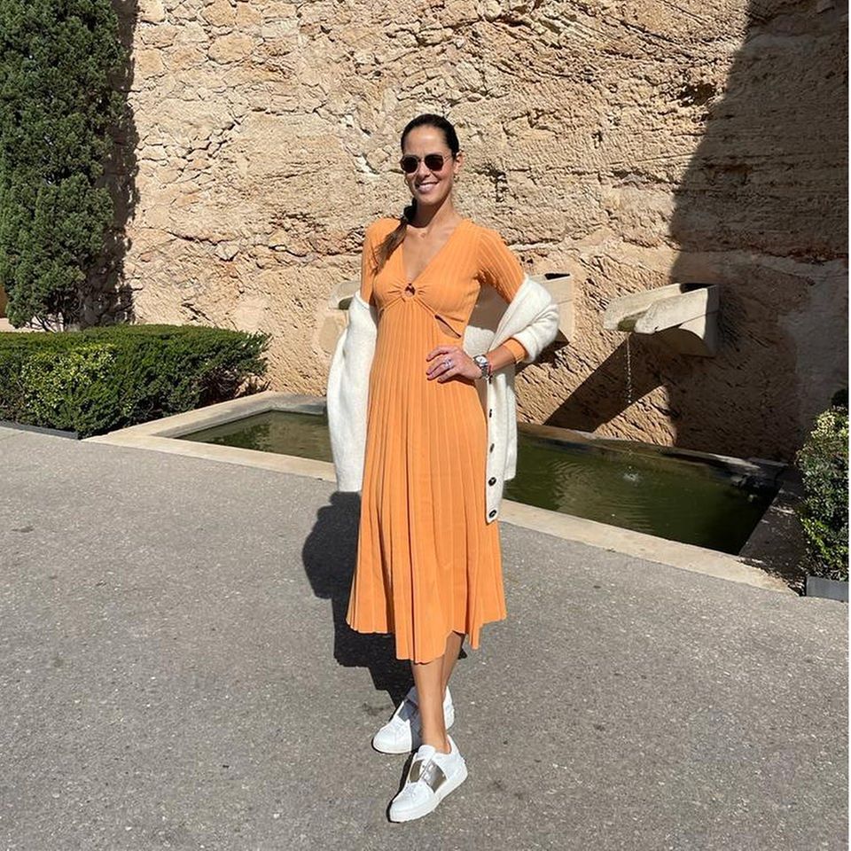 Dass sie die sommerlichen Temperaturen und die Sonne genießt, zeigt Ana Ivanović auf Instagram. Beim Spaziergang im Park posiert sie mit einem Midikleid mit Cut-Out-Details in der Sommerfarbe Orange. Dazu stylt sie weiß-goldene Sneaker, eine weiße Strickjacke und eine Sonnenbrille.