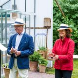 König Carl Gustaf und Königin Silvia stehen vor einem Gewächshaus.