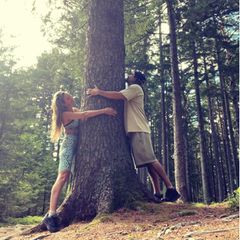 Heidi Klum und Tom Kaulitz umarmen einen Baum.