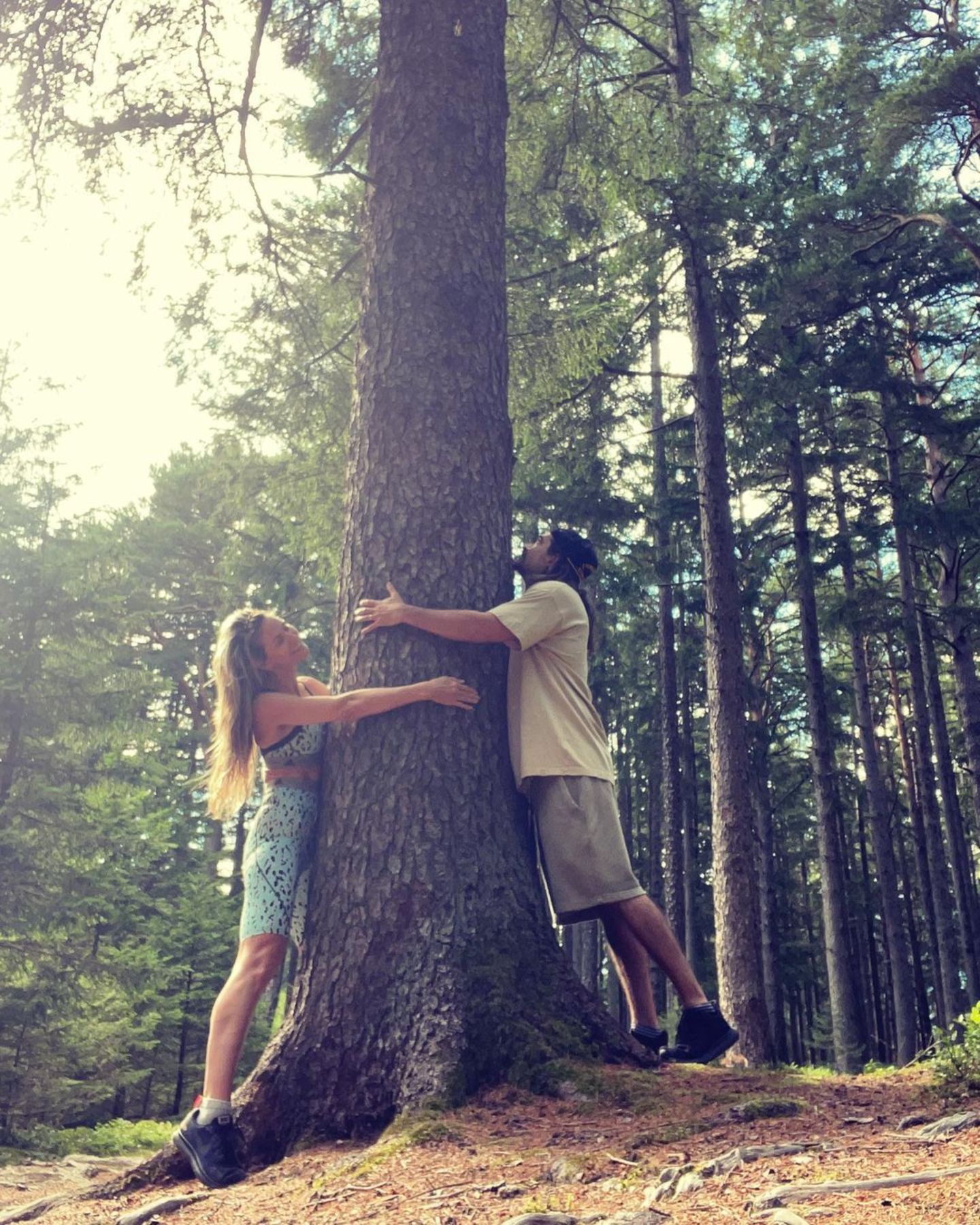 Heidi Klum und Tom Kaulitz umarmen einen Baum.