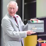 Prinz Charles hält eine TV-Klappe in der Hand.