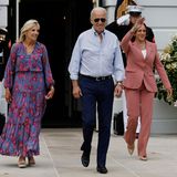 Kamala Harris winkt an der Seite von US-Präsident Joe Biden freudig den Fotograf:innen. Ihr Strahlen im Gesicht wird von ihrem roséfarbenen Zweiteiler optisch unterstrichen. Eine doppelreihige Perlenkette sowie beigefarbene Pumps komplettieren ihren sommerlichen Business-Look. 