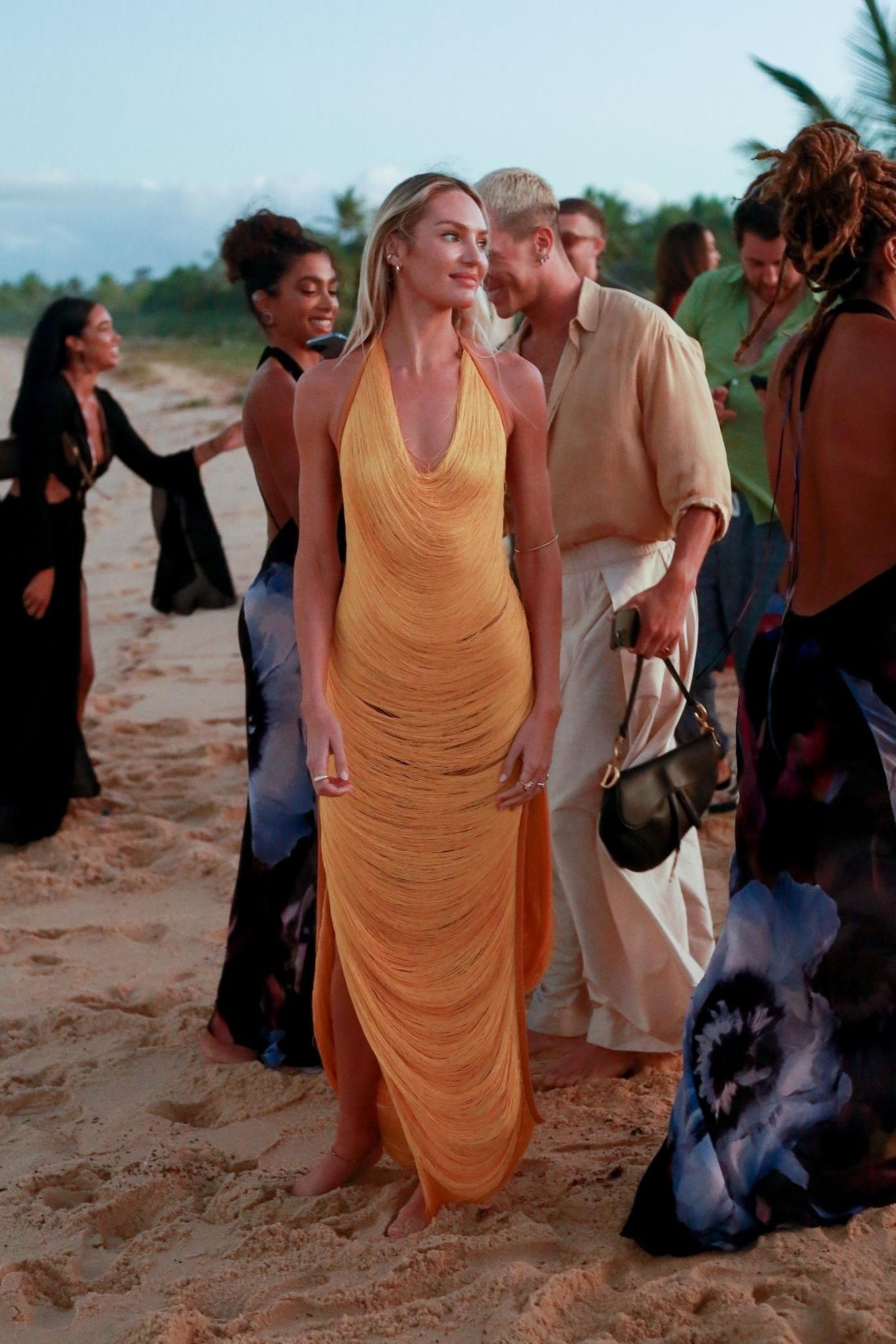 Seit Jahren legt Candice Swanepoel Wow-Auftritte auf dem Runway hin, doch auch bei der Hochzeit ihrer Model-Freundin Lais Ribeiro ist sie im gelben Fadenkleid der absolute Hingucker. Die Fäden, die locker ihre Silhouette umspielen, schimmern im warmen Sonnenuntergang – das perfekte Kleid für eine Hochzeit am Strand. 
