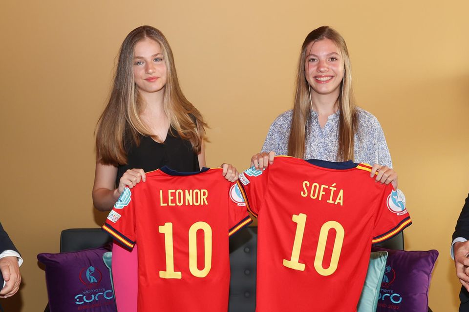 Prinzessin Sofia von Spanien: Das dritte Gruppenspiel der spanischen Frauenfußball-Nationalmannschaft bei der UEFA Women’s Euro 2022 schauten sich Prinzessin Leonor und Prinzessin Sofia vor Ort im englischen Brentford an. Passend dazu erhalten die Schwestern personalisierte Trikots, die sie freudig in die Kamera halten. Ihr Stadion-Look ist sportlich-feminin: Während Sofia eine Blumen-Bluse von & Other Stories trägt, wählt Leonor eine pinkfarbene Stoffhose aus und kombiniert dazu ein schwarzes Shirt. Das dritte Gruppenspiel der spanischen Frauenfußball-Nationalmannschaft bei der UEFA Women’s Euro 2022 schauten sich Prinzessin Leonor und Prinzessin Sofia vor Ort im englischen Brentford an. Passend dazu erhalten die Schwestern personalisierte Trikots, die sie freudig in die Kamera halten. Ihr Stadion-Look ist sportlich-feminin: Während Sofia eine Blumen-Bluse von & Other Stories trägt, wählt Leonor eine pinkfarbene Stoffhose aus und kombiniert dazu ein schwarzes Shirt.