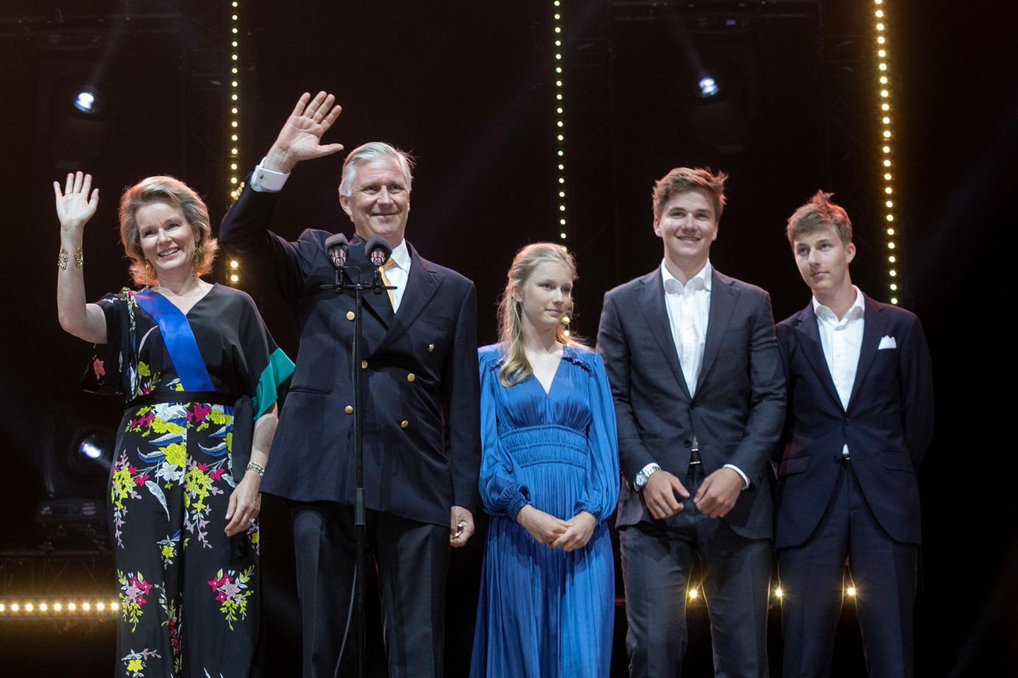 Belgische Königsfamilie: Köngin Mathilde und König Philippe und ihre Kinder stehen auf einer Bühne.