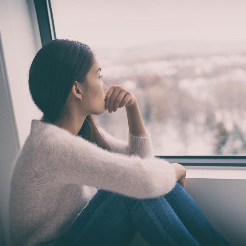 Frau schaut nachdenklich aus dem Fenster: So verändert Stress unsere Persönlichkeit