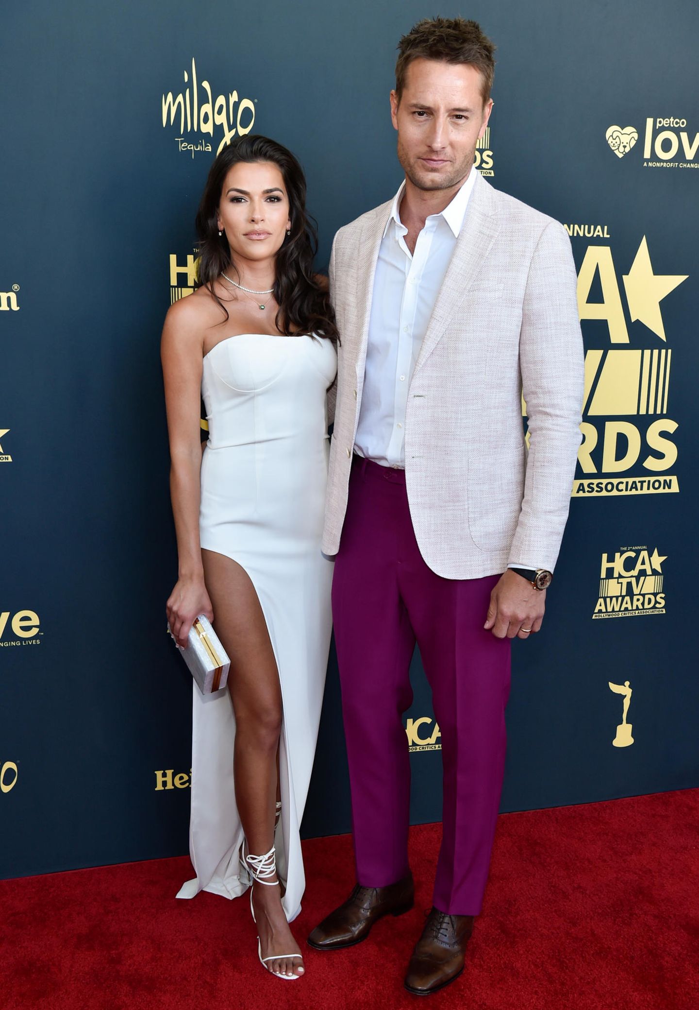 Justin Hartley bringt farblichen Kontrast auf den Red Carpet. Bei den HCA TV Awards trägt er eine violettfarbene Stoffhose zum weißen Hemd und Leinenblazer. Seine Ehefrau Sofia Pernas ist da etwas zurückhaltender und wählt eine weiße Robe mit großem Beinausschnitt. 