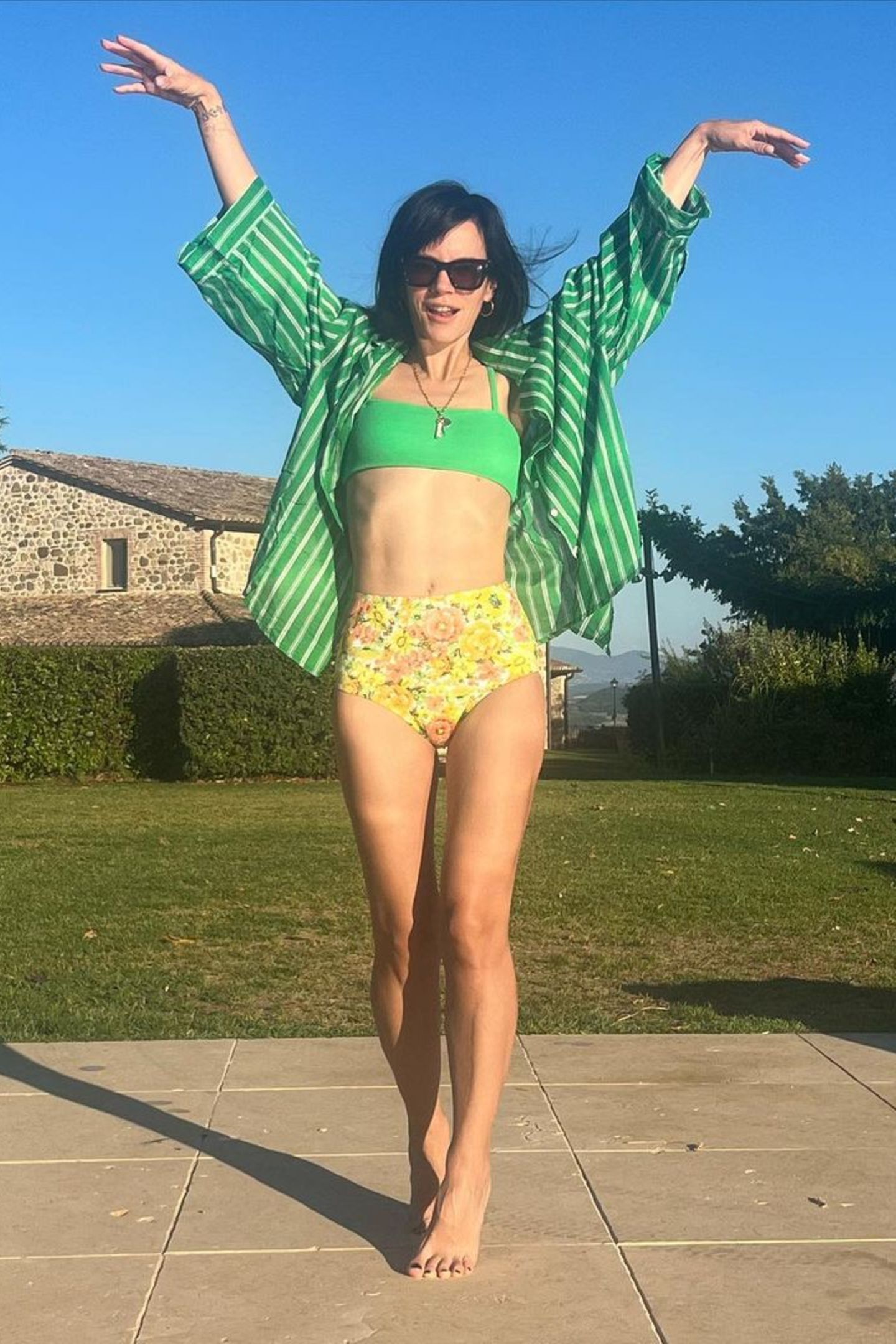 In Italien lässt Lily Allen sich von der Sonne verwöhnen. Passend zu dem warmen Wetter posiert sie in einer Blumen-Muster-Bikinihose. Das gelbfarbene High-Waist-Höschen kombiniert sie mit einem knallgrünen Bikinitop. Für ein wenig Abdeckung sorgt eine grün-weiß gestreifte Bluse. Der luftige Look schreit förmlich nach Sommer.