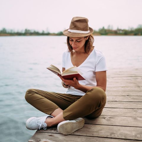 Frau liest am See: Diese 4 lustigen Liebesromane werden Sie tiefer berühren als gedacht