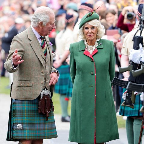 Prinz Charles und Herzogin Camilla sind zum Braemar Gathering gereist, um bei den bekanntesten Highland Games in Schottland zuzuschauen. Herzogin Camilla hat sich bei  dem Termin optisch an Prinz Charles und seinem grünen Kilt orientiert. Sie trägt einen tannengrünen Mantel, der an den Ärmeln und am Kragen mit schottischem Tartan versehen ist. Dazu kombiniert sie eine weiße Bluse mit Rüschenkragen und einen Hut mit Federdetail. 
