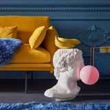 Wenn Klassik auf Modern trifft: Antike Kunst mit knalligen Akzenten. Der Beistelltisch ist ein Statement-Piece, welcher als Hingucker dient. Die pinkfarbene Kaugummiblase setzt dem gelbfarbenen Sofa einen Kontrast.