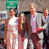 Bei ihrem Besuch in Düsseldorf zeigen sich Herzogin Meghan und Prinz Harry nicht nur gut gelaunt, sondern auch in Looks, die aufeinander abgestimmt scheinen. Die Herzogin trägt eine auf der Taille sitzende Hose von Brandon Maxwell (Kostenpunkt: 1.000 Euro), dazu ein Neckholder-Top von Anine Bing sowie weiße Pumos. Harry erscheint im klassischen Anzug in einem Graubraun mit weißem Hemd und braunen Wildlederschuhen.