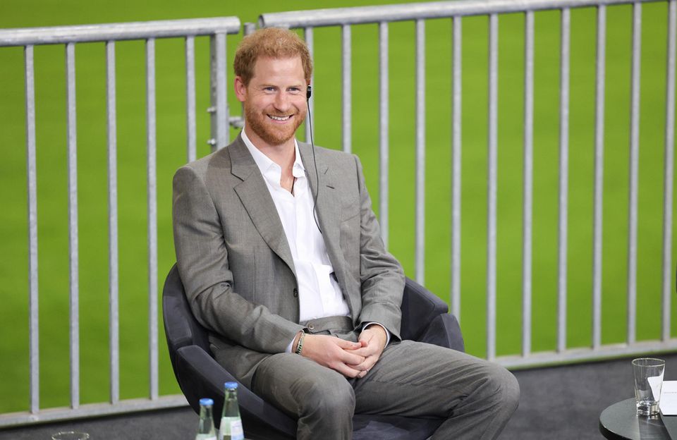 Während der Pressekonferenz kann sich Prinz Harry einen kleinen Scherz nicht verkneifen: Er witzelt über die dramatische Musik, die über die Stadion-Lautsprecher ertönt. Während der Pressekonferenz kann sich Prinz Harry einen kleinen Scherz nicht verkneifen: Er witzelt über die dramatische Musik, die über die Stadion-Lautsprecher ertönt.