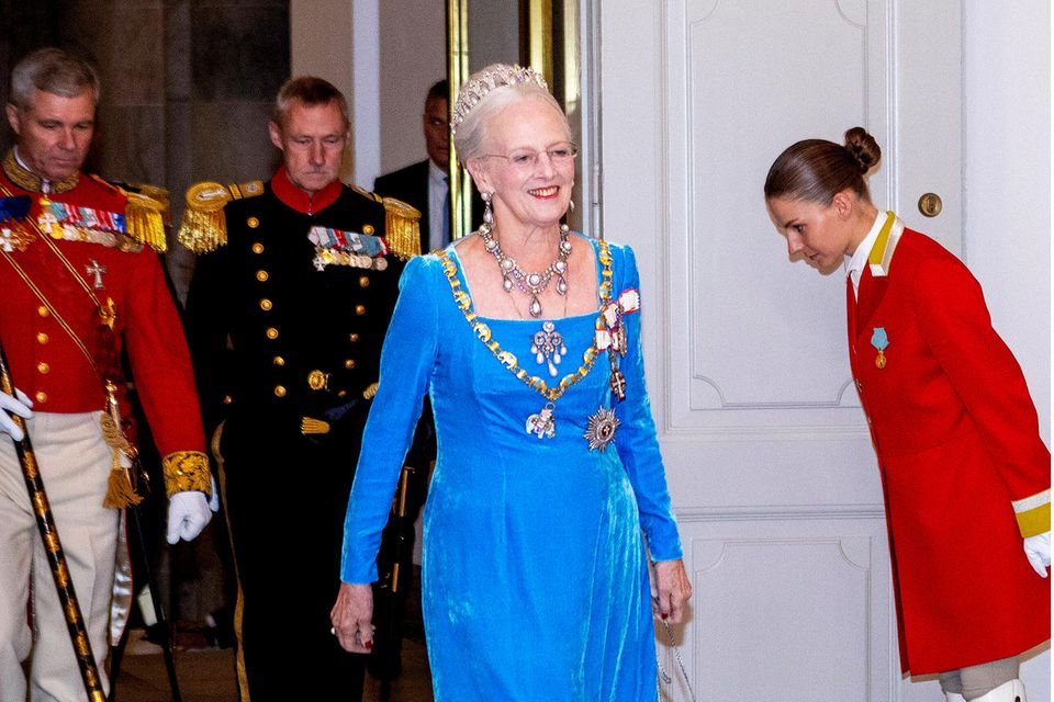 Die Königin selbst bezaubert nämlich in einer eleganten, meerblauen Samtrobe mit königlichem Ornat, prachtvoller Perlenkette und der Perlentropfen-Tiara.