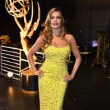 Mit Sofía Vergara scheint auch im dunklen Backstage-Bereich der Emmys die Sonne: Sie trägt einen figurbetonten Look von Laura Basci in Gelb.