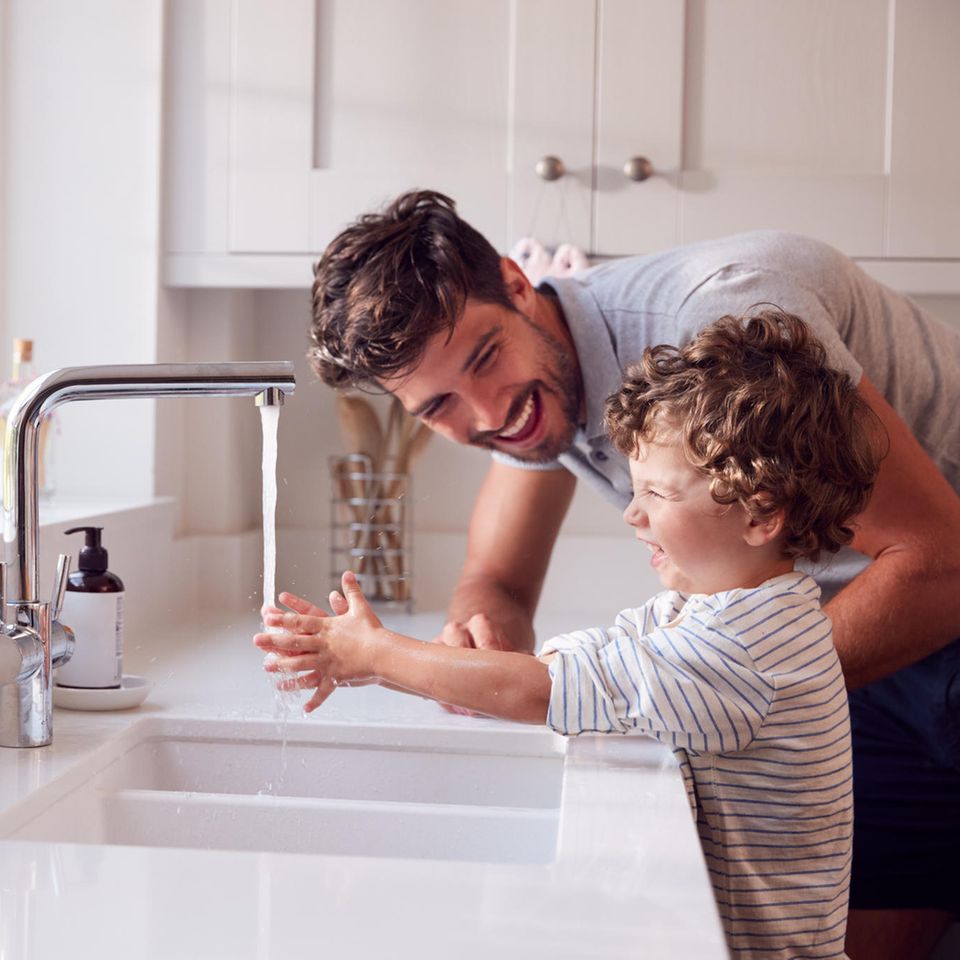 Vater und Kind waschen sich in der Küche die Hände am Waschbecken