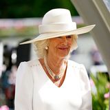 Beim Pferderennen in Ascot zeigt sich Camilla in einem stylischen All-White-Look, der eine gewisse Leichtigkeit ausstrahlt. Die vierreihige Perlenkette ist eines ihrer Lieblingsschmuckstücke. Mit einem XXL-Hut macht sie das Outfit perfekt.