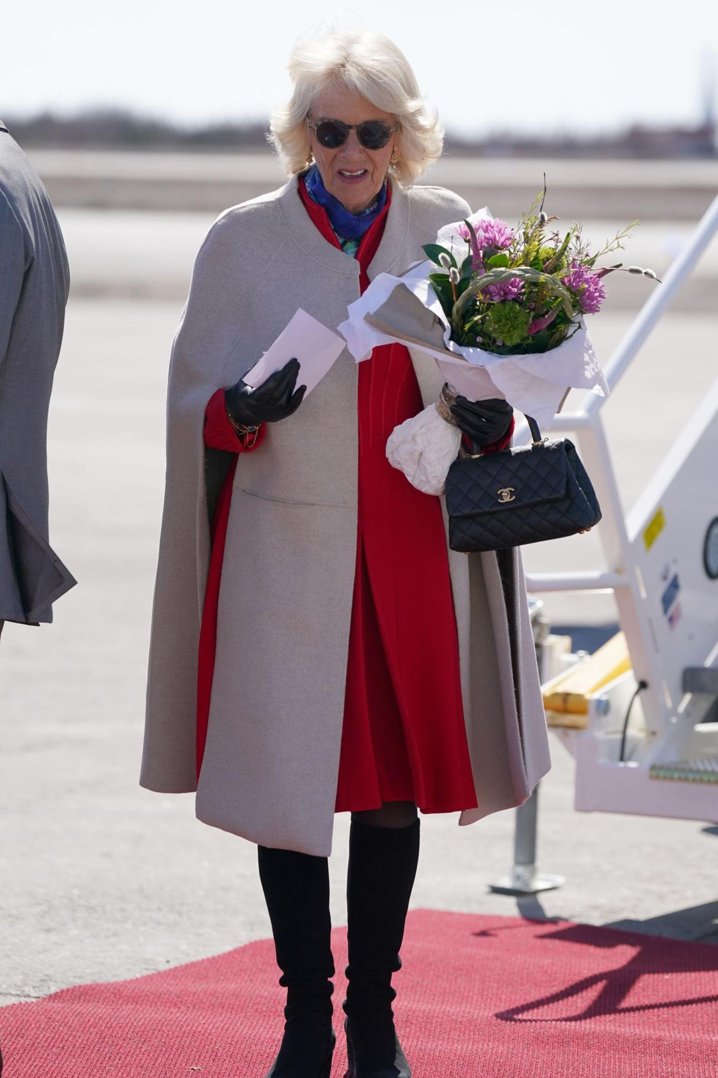 Ein klassisches Accessoire für eine elegante Frau. Mit einem Chanel Täschchen in der Hand steigt Königin Camilla in Kanada aus dem Flugzeug. Dazu kombiniert sie einen stylischen Poncho und hohe Stiefel.