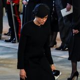 Bei der Überführung des Sarges von Queen Elizabeth nach Westminster Hall zeigt sich Meghan in einem schwarzen Givenchy-Mantel, dazu trägt sie einen Fascinator mit Netzteil. Eine nette Geste für die verstorbene Queen sind ihre Ohrringe.