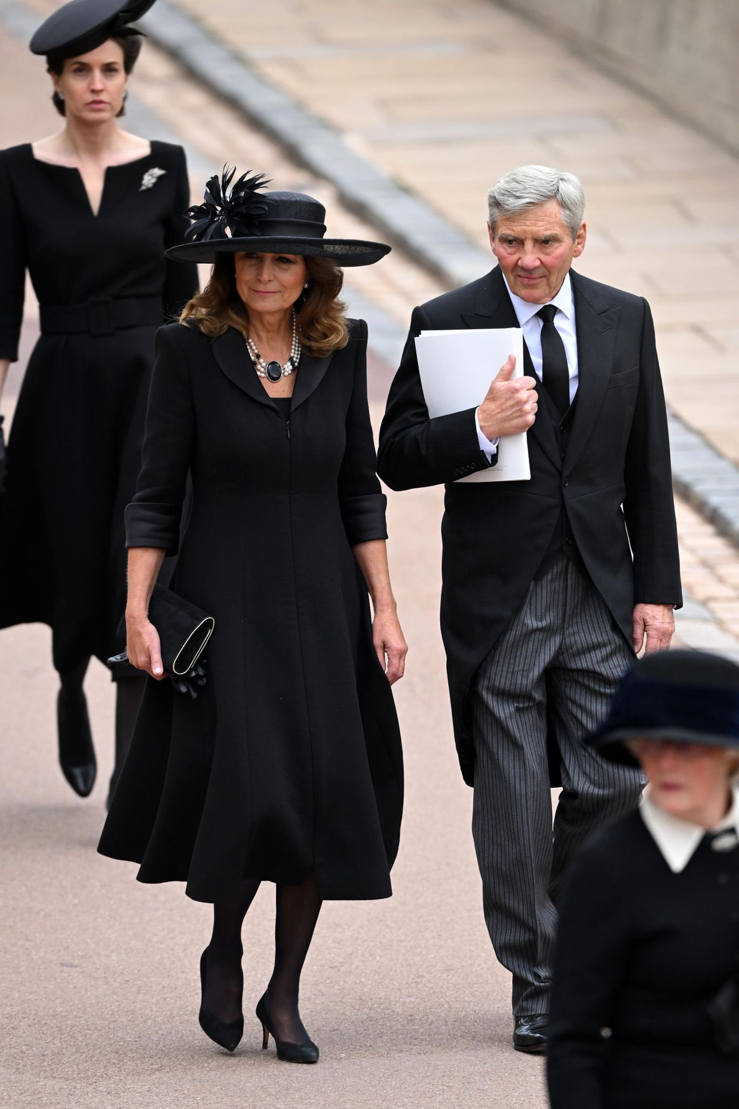 Auch Kates Eltern, Carole und Michael Middleton, zählen zu den Gästen der Beerdigung. Zu ihrem schlichten Mantelkleid von Catherine Walker trägt sie ein dreistrangiges Perlen-Collier mit auffälligem Anhänger, welches alle Blicke auf sich zieht. 