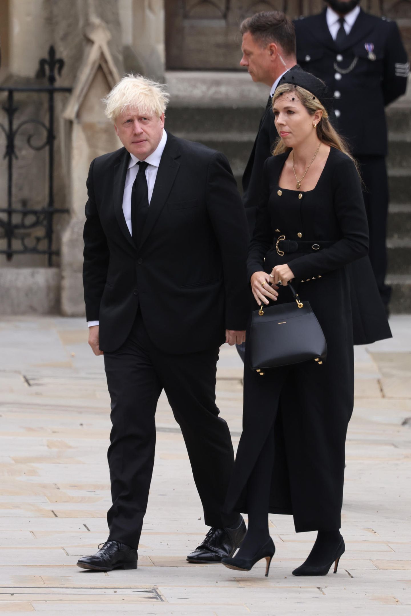Der ehemalige Premierminister Boris Johnson und seine Frau Carrie kommen an der Kirche an. Carrie trägt ein Kleid von Karen Millen, das durch seine doppelreihige Knopfleiste auffällt. In der Hand hält sie die "Love Letter"-Tasche von Grace Han, die auch Kate besitzt und liebt. 