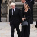 Der ehemalige Premierminister Boris Johnson und seine Frau Carrie kommen an der Kirche an. Carrie trägt ein Kleid von Karen Millen, das durch seine doppelreihige Knopfleiste auffällt. In der Hand hält sie die "Love Letter"-Tasche von Grace Han, die auch Kate besitzt und liebt. 