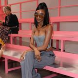 Jourdan Dunn nimmt in der pinkfarbenen Front Row von Fendi Platz. Sie trägt einen gemusterten Zweiteiler bestehend aus weit geschnittener Hose und Korsagentop. 
