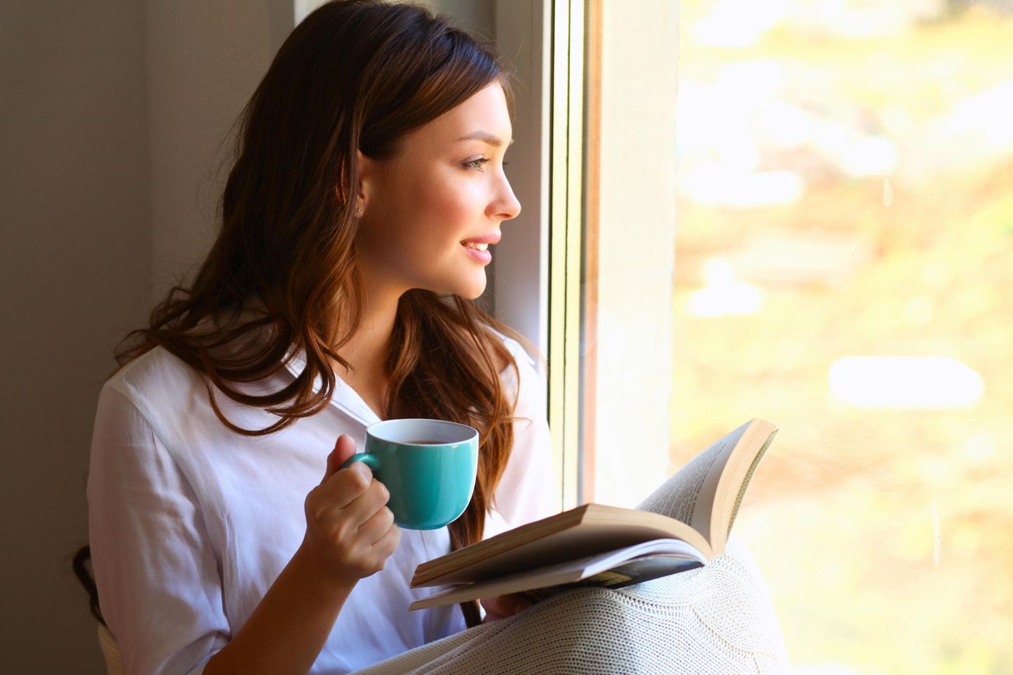 Woman with book by the window, book trends autumn