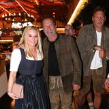 Auch Arnold Schwarzenegger zeigt sich an der Seite von Freundin Heather Milligan in klassischer Ledertracht. Sie bricht die dunklen Töne ihres Kleides mit roséfarbenen, spitzen Pumps und einer passenden Tasche auf und bringt so eine Extraportion Pep in ihr Oktoberfestoutfit.