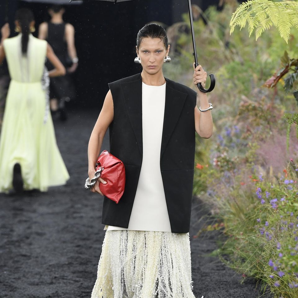 Jil Sander beweist mit einem Outdoor-Garten-Runway, dass auch Regen den Spring/Summer-Designs nichts anhaben kann. Stylisch geht es bei dem deutschen Label mit übergroßem Regenschirm über den Catwalk.