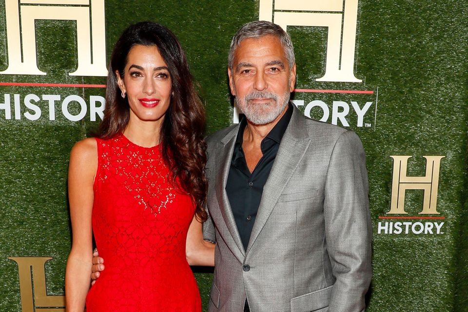 Wenn es ums Styling geht, dann weiß Amal Clooney ganz genau, womit sie punkten kann. Bei den "HISTORYtalks" in Washington trägt sie einen roten Spitzen-Jumpsuit und roten Lippenstift. Neben ihr sticht Ehemann George in seinem grauen Anzug nicht sehr stark hervor. Ob er das bereits gewohnt ist?