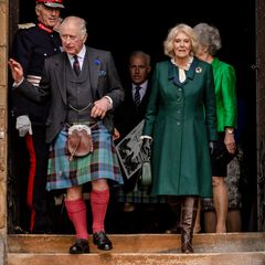 Für ihren ersten gemeinsamen Auftritt als neues Königspaar nach der offiziellen Trauerzeit besuchen Charles und Camilla die Stadt Dunfermline in Schottland. Und nicht nur der König kleidet sich mit Schottenrock dem Anlass und Ort entsprechend würdigend, auch die Queen Consort trifft mit ihrem dunkelgrünen Mantel mit blaugrün kariertem Innenfutter genau den richtigen (Farb-)Ton. Drunter trägt sie eine cremefarbene Bluse mit Rüschenkragen- und saum, und weil es schon recht herbstlich ist in Schottland dazu feste braune Lederstiefel.