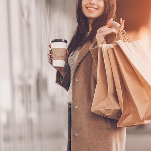 Frau mit Shoppingtüten und Kaffee: Wer Kaffee trinkt, gibt mehr Geld aus