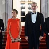 Königin Letizia macht ihren Besuch in Deutschland zur Reise der starken Farben und entzückt beim Staatsdinner in Berlin im feuerroten "Cecelia"-Capekleid von Stella McCartney. Zu ihrer asymmetrischen Robe stylt die 50-Jährige eine goldene Clutch von Magrit sowie goldene Plateau-Heels von Jimmy Choo. Die Haare der Königin sind zu einer eleganten Hochsteckfrisur zurückgebunden, sodass Schulterpartie des Kleides und Accessoires perfekt wirken können.