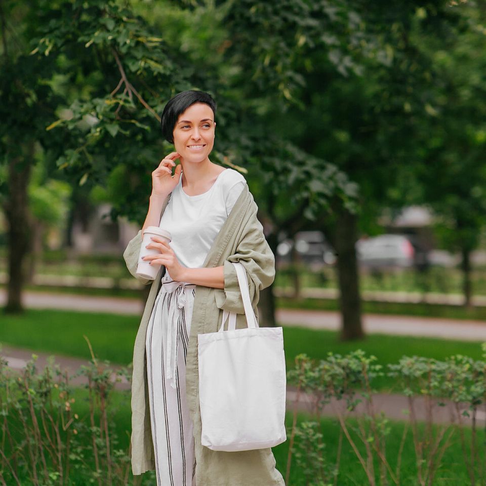 Nachhaltig leben: Frau mit Baumwolltasche und Coffee to go-Becher