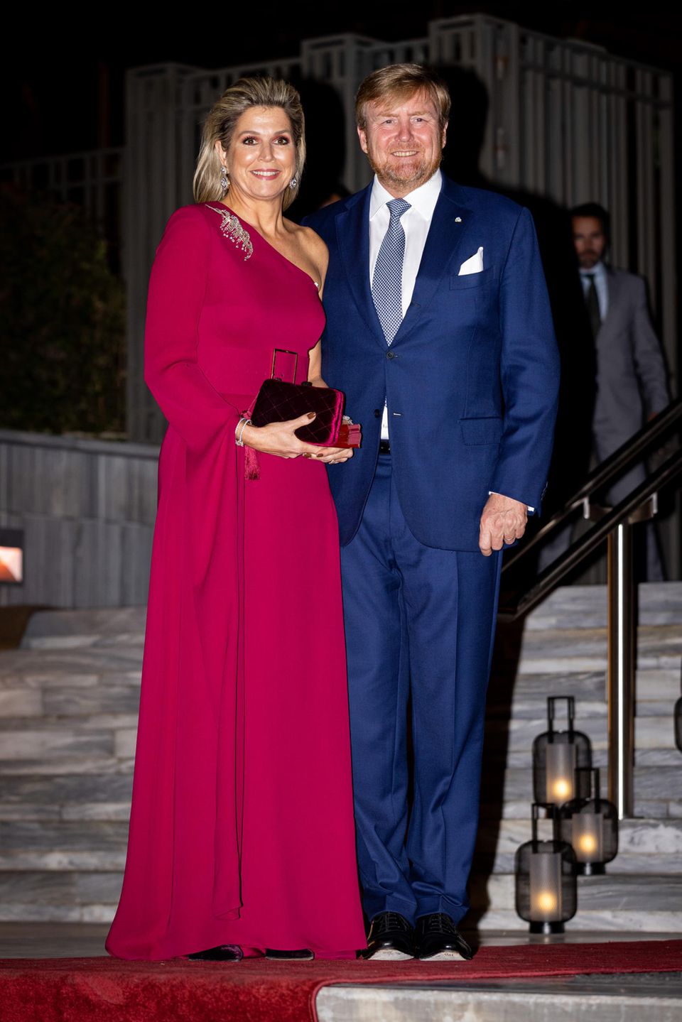 Am dritten Tag ihres Staatsbesuchs in Griechenland beweisen Königin Máxima und König Willem-Alexander ihr Trend-Gespür! In einem monochromen Look, wie es für den Herbst und Winter bereits auf den Laufstegen von Valentino oder Max Mara zu sehen war, hält sich Königin Máxima an ein knalliges Burgunder: Eine bodenlange Robe von Claes Iversen betont durch den Gürtel ihre wunderschöne Taille, während die passenden Samtschuhe und die feine Clutch sich perfekt in den Look integrieren. Gatte Willem-Alexander wählt einen Anzug in einem satten Blau und trifft damit die Hofetikette. Am dritten Tag ihres Staatsbesuchs in Griechenland beweisen Königin Máxima und König Willem-Alexander ihr Trend-Gespür! In einem monochromen Look, wie es für den Herbst und Winter bereits auf den Laufstegen von Valentino oder Max Mara zu sehen war, hält sich Königin Máxima an ein knalliges Burgunder: Eine bodenlange Robe von Claes Iversen betont durch den Gürtel ihre wunderschöne Taille, während die passenden Samtschuhe und die feine Clutch sich perfekt in den Look integrieren. Gatte Willem-Alexander wählt einen Anzug in einem satten Blau und trifft damit die Hofetikette.