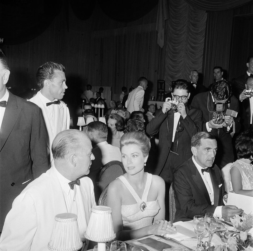 Trotz des ihres Kummers muss die Fürstin ihre Pflichten weiter wahrnehmen: US-General Seitz, Grace Kelly und Roger Crovetto, ein monegassischer Beamter (v.l.n.r.), bei einer Gala des Roten Kreuzes in Monaco am 27. Juli 1962.