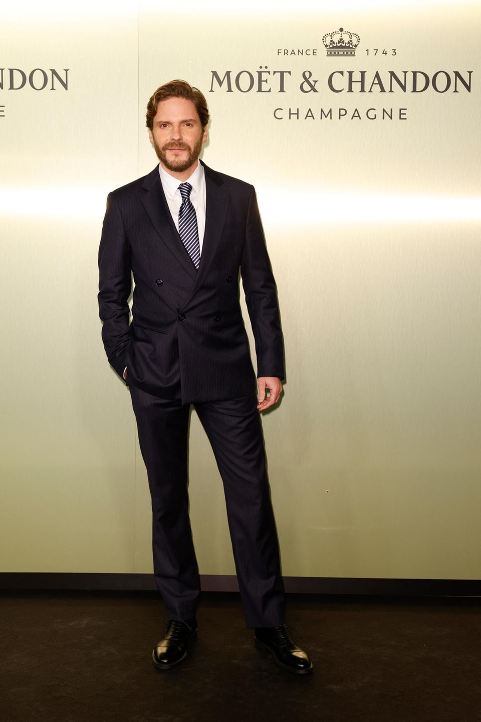 Im dunkelblauen Anzug und mit gestreifter Krawatte sorgt Daniel Brühl für deutschen Hollywood-Glam auf der promibesetzten Party. 