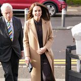 Catherine, Princess of Wales, zeigt sich in einem dunkelblauen Kleid mit gelben Punkten vom Londoner Label LK Bennett (Preis rund 420 Euro). Das Hemdblusenkleid besticht durch seinen leicht durchsichtigen, fließenden Stoff. Für einen offiziellen Auftritt definitiv eine gewagte Wahl. Dank Unterkleid und Wollmantel wirkt der Look dennoch nicht freizügig. Dazu kombiniert Kate blaue Wildlederpumps und eine Clutch. Sie verzichtet auf Locken, trägt das Haar glatt geföhnt. 