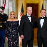 First Lady Dr. Jill Biden hat sich für einen nachtblauen Spitzenlook mit Blumenmotiven entschieden, die Première Dame Brigitte Macron strahlt in einem weßen Gala-Dress mit silbernen Schmuck-Applikationen und passender Clutch.
