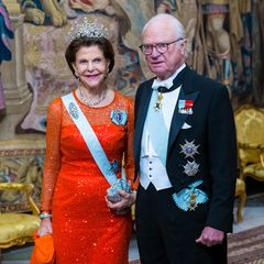 Das Königsdinner am Tag nach der Nobelpreisverleihung in Stockholm ist ein zweiter schöner Anlass für die royalen Damen, sich von ihrer glamourösesten Seite zu zeigen. Mit König Carl Gustaf im feierlichen Frack an ihrer Seite glitzert Königin Silvia in diesem Jahr in einem eleganten Abendkleid in kräftigem Orangerot.