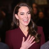 Kate strahlt, als sie die Gäste begrüßt. Ihre elegant gewellten Haare sind so gestylt, dass sie den Blick auf die hängenden Ohrringe mit passenden Steinen freilegen. 