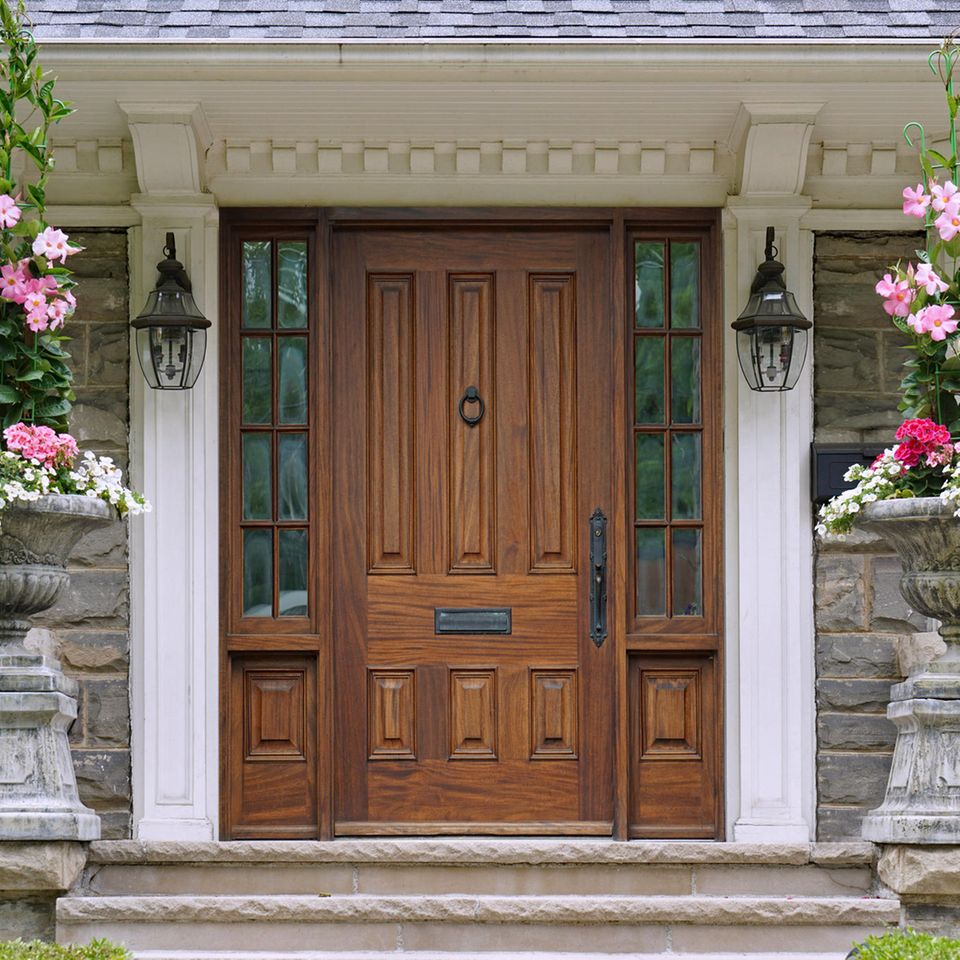 Ein hübscher Hauseingang mit imposanter Holztür uns Blumensäulen