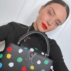 Mit farblich passendem Lippenstift posiert Miranda Kerr samt Louis Vuitton x Yayoi Kusama Tasche auf Instagram. Das Rot der Tasche greift sie neben dem Lippenstift außerdem in ihrem Lidschatten und Blush auf. Zusammen mit dem Sleek-Bun gibt sie dem Look einen eleganten Touch. 