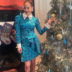 Nicht cool, sondern süße mag es Jennifer Lopez zu Weihnachten. Im kurzen Minikleid mit Schleifen-Print und Spitzkragen posiert sie vor dem farblich passend geschmückten Weihnachtsbaum. 