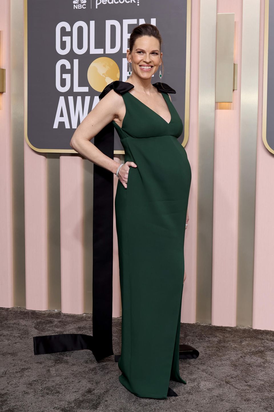 Hilary Swank erwartet ihr erstes Baby. Die Vorfreude auf den Familienzuwachs ist ihr ins Gesicht geschrieben. Im moosgrünen Kleid mit tiefem V-Ausschnitt setzt sie ihre Kugel bei den Golden Globe Awards stolz in Szene.