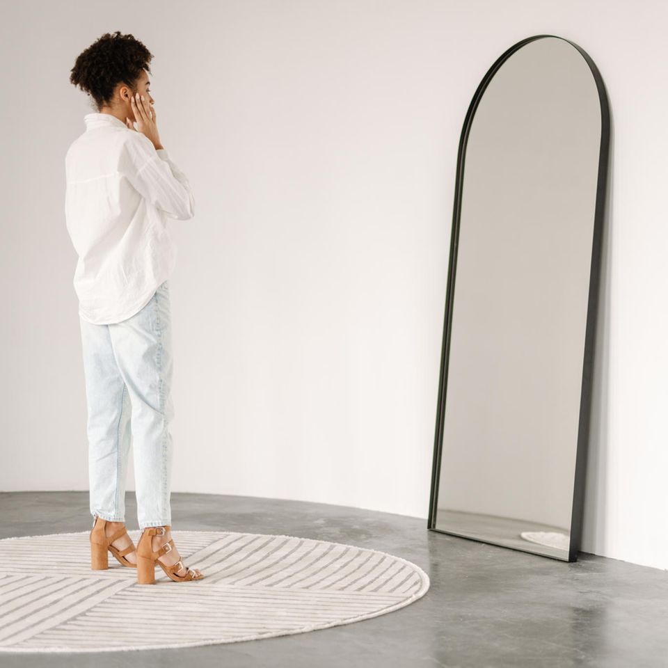 Frau steht vor dem Spiegel: Gesundes Selbstbewusstsein oder Narzissmus? Das ist der Unterschied