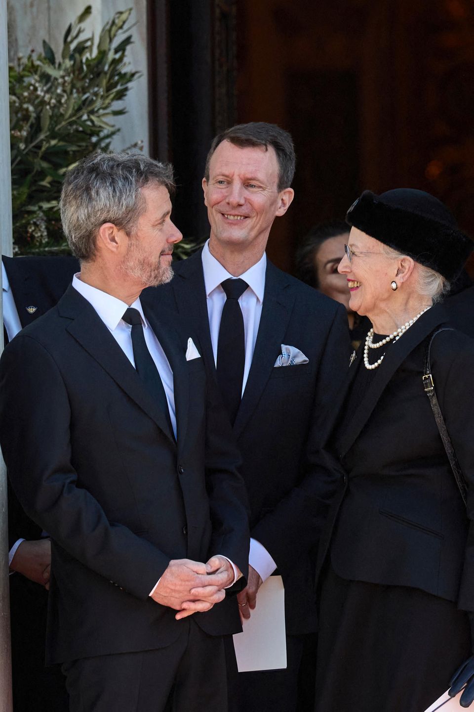 Prinz Frederik (li.), Prinz Joachim und Königin Margrethe lachen herzlich bei der Beerdigung von Konstantin von Griechenland am 16. Januar 2023 in Athen.