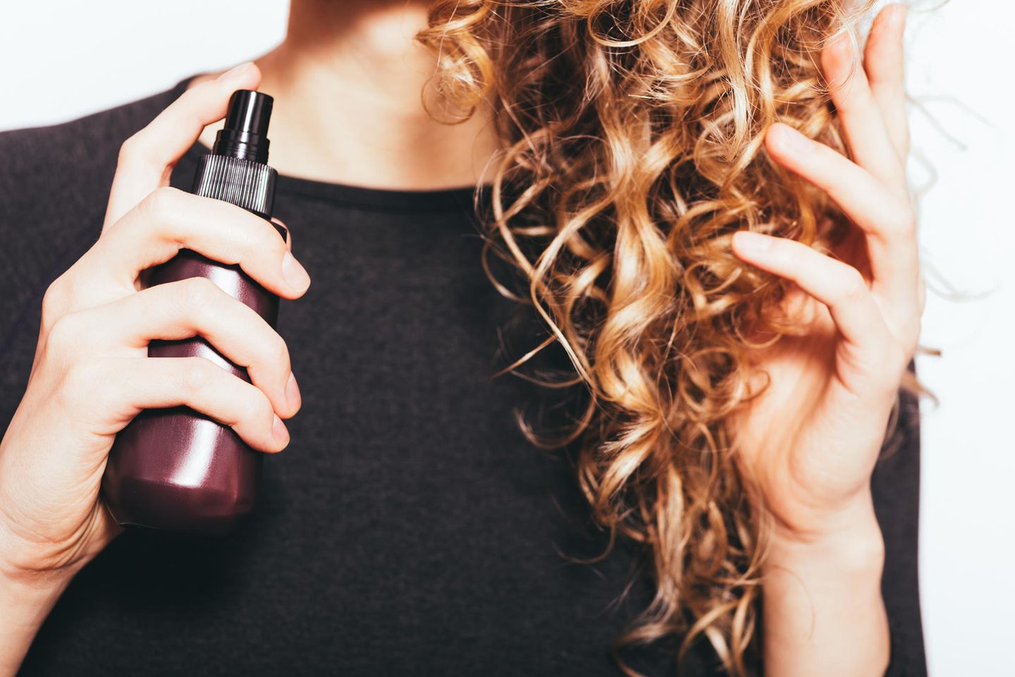 Frizz adé: 5 einfache Tipps gegen krause Haare, Frau mit Locken und Spray